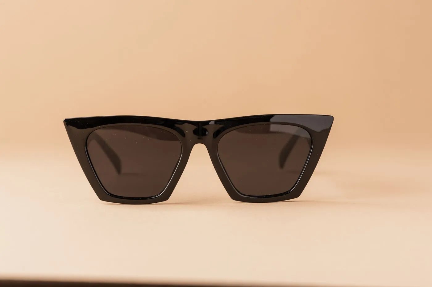 Lunettes de soleil œil-de-chat noires sur fond beige